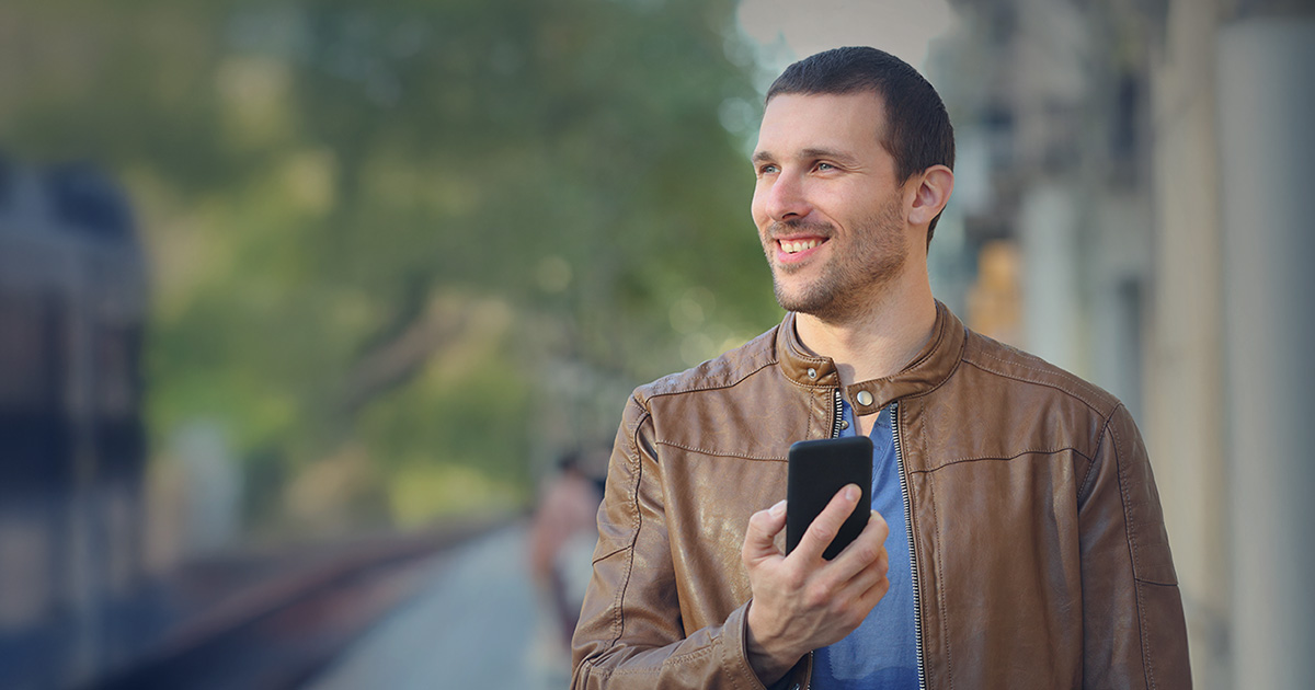 Cheerful man using smartphone on MetroLink platform